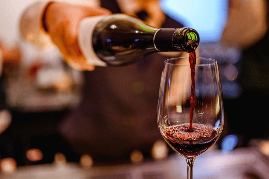 waiter pouring red wine into a wine glass at a wine bar